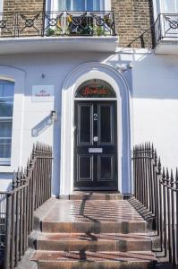 - une porte noire dans un bâtiment blanc avec des escaliers dans l'établissement The Hurdwick, à Londres