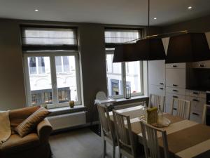 uma cozinha e sala de jantar com uma mesa e 2 janelas em Zucchero Apartment Brugge em Bruges