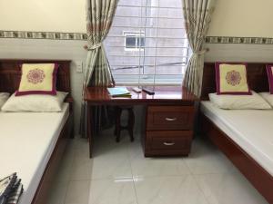 a room with two beds with a desk and a window at Hoang Oanh Motel in Long Hai