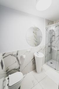 La salle de bains blanche est pourvue de toilettes et d'un lavabo. dans l'établissement Apartament Słoneczny, à Uniejów