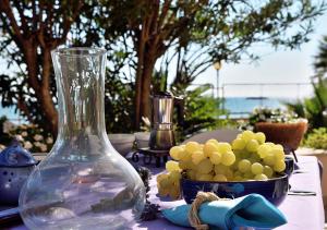 a table with a glass vase and a bowl of grapes at Villa Metis in Realmonte +38 photos