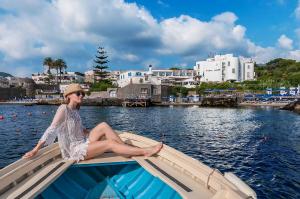 Una donna seduta su una barca in acqua di Punta Molino Beach Resort & Thermal Spa a Ischia