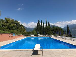 a swimming pool with chairs and trees and mountains at Terrazze - Luxury Lake Como View Apartment - in Menaggio in Menaggio
