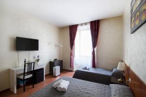 una camera con 2 letti, una scrivania e una TV di Roma Enrico Guesthouse a Roma