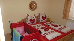 una cama roja con almohadas de corazones encima en Vronis Landhaus Apartments en Hüttau