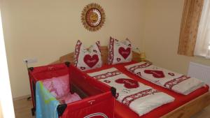 a red bed with hearts pillows on top of it at Vronis Landhaus Apartments in Hüttau