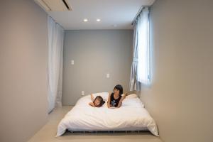 a woman and a child laying on a bed at Crasco TABI-NE in Kanazawa