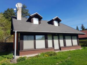 una casa con techo de gambrel con ventanas y chimenea en Garden View, en Drienica