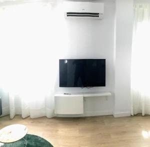 einen Flachbild-TV auf einem weißen Stand im Wohnzimmer in der Unterkunft El Rincon de Miguel junto al Guadalquivir in Sevilla