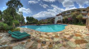 a swimming pool with two lounge chairs and a building at Posada de la Mision, Hotel Museo y Jardin in Taxco de Alarcón
