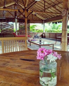 un vase rempli de fleurs assis sur une table en bois dans l'établissement Pondok Bamboo Sendangsari, à Wonosobo