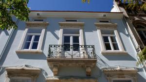 een wit gebouw met een balkon en ramen bij WW Hostel & Suites in Coimbra