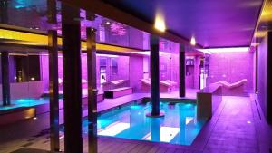 プラヤ・デアロにあるCosmopolita Hotel Boutique & Spaの紫色の照明を用いた建物内のスイミングプール