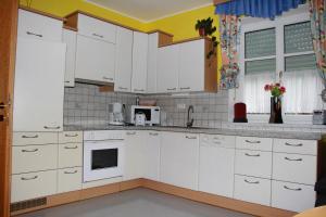 a kitchen with white cabinets and a microwave at Ferienwohnung Wurm in Anger