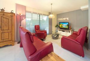 バニョル・アン・フォレにあるVilla Quietudeのリビングルーム(赤い椅子、テレビ付)