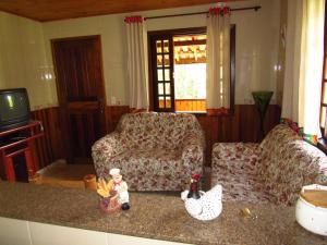 uma sala de estar com um sofá e uma cadeira em Chalé Caminho Das Cachoeiras em Visconde de Mauá