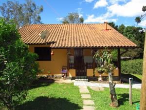 una pequeña casa amarilla con techo de baldosa en Chalé Caminho Das Cachoeiras, en Visconde De Maua