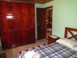 um quarto com uma cama e alguns armários de madeira em Chalé Caminho Das Cachoeiras em Visconde de Mauá