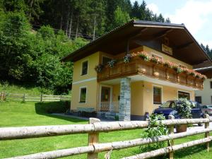 ein gelbes Haus mit einem Balkon mit Blumen darauf in der Unterkunft Vronis Landhaus Apartments in Hüttau