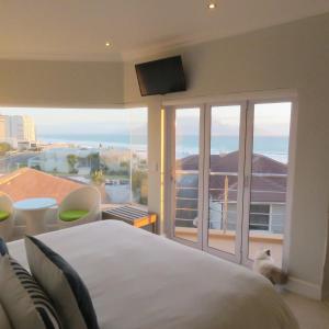 a bedroom with a bed and a view of the ocean at Gull on the Bay Boutique Guest House in Bloubergstrand