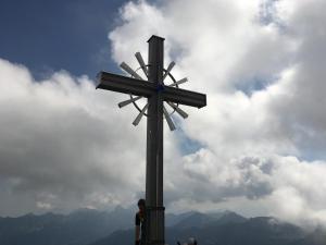 una persona in piedi accanto a una croce sulla cima di una montagna di Haus Romantika a Schattwald