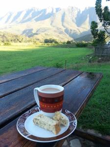 a cup of coffee and cookies on a wooden table at Die Hoenderhok and Die Plaashuisie in Swellendam +24 photos