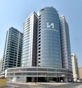 un gran edificio de cristal con un cartel. en Swiss-Belresidences Juffair en Manama