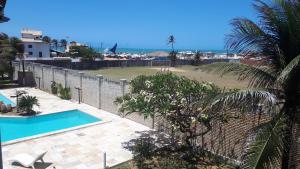 a fence next to a swimming pool with a beach at Villa Orazio Prainha in Prainha