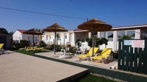 a patio with yellow chairs and umbrellas at Apartamentos na Quinta Altavista do Carvalhal in Zambujeira do Mar
