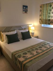a bedroom with a large bed with green pillows at Apartamento Pé na Areia, Clube Nautilus, Porches in Armação de Pêra