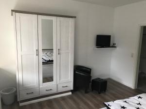 a bedroom with a white cabinet and a black chair at Hademarscher Hof in Hanerau-Hademarschen