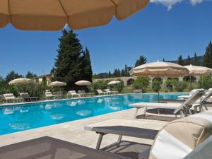 a swimming pool with chairs and umbrellas in a resort at Hotel-Restaurant Le Moulin De La Camandoule in Fayence