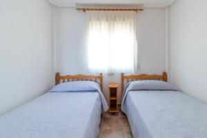 2 camas individuales en una habitación con ventana en Urbanización Cala fría (Faro Cabo de Palos) en Cabo de Palos