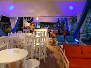 a restaurant with white tables and chairs and a bar at Hotel ANTAG in Shëngjin