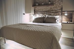 a large bed in a bedroom with a brick wall at Al Mattina Apartments Belgrade in Belgrade