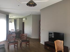 a living room with a table and chairs and a television at Apries de Sais - villa de standing avec piscine in Aogan