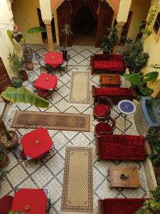 um quarto com cadeiras vermelhas, mesas e plantas em Riad Marlinea em Salé
