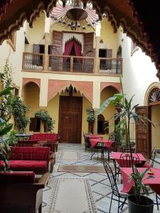 a building with red couches and tables and a balcony at Riad Marlinea in Sale