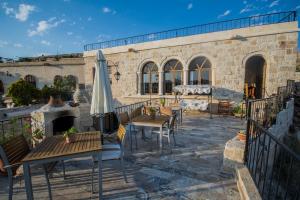 an outdoor patio with tables and an umbrella at Assiana Cave Hotel in Ürgüp