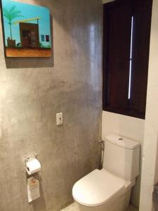 a bathroom with a toilet and a painting on the wall at De Lanna Hotel in Chiang Mai
