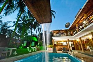 a swimming pool with a waterfall in a house at Pousada Lua Cheia in Praia do Frances