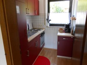 コッヘムにあるHaus Antjeのキッチン(赤いキャビネット、シンク、窓付)