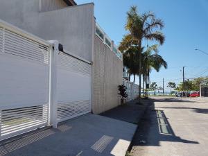 a building with a white garage door next to a sidewalk at Pousada Char in Ubatuba