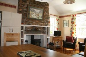 a living room with a fireplace and a table at Laich Cottage in Appin