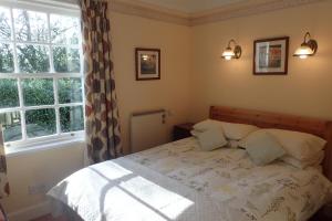 1 dormitorio con 1 cama con 2 almohadas y ventana en Laich Cottage, en Appin