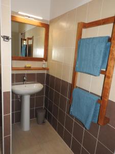 La salle de bains est pourvue d'un lavabo, d'un miroir et de serviettes bleues. dans l'établissement Kreyol Eden Cottage, au Gosier