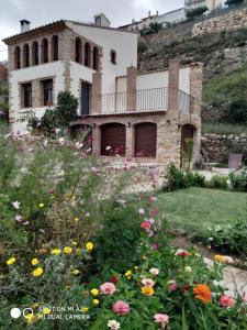 a house on a hill with flowers in front of it at Casa Rural Caseta de l' Hort in Villafranca del Cid