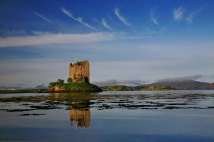 a castle on an island in a body of water at Laich Cottage in Appin