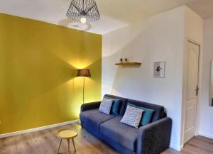 sala de estar con sofá azul y pared amarilla en Les Appartements d'Edmond Sylvabelle, en Marsella