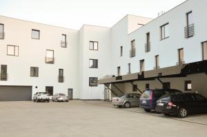 a large white building with cars parked in a parking lot at Rezidencia Amélia in Bardejovské Kúpele